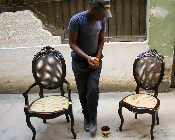 A man polishing two ornate chairs