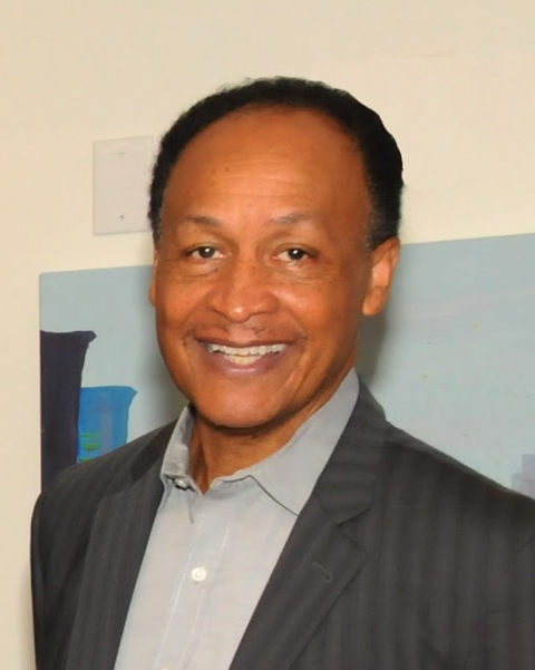 Linwood Ogelsby in a grey suit with landscape painting in the background